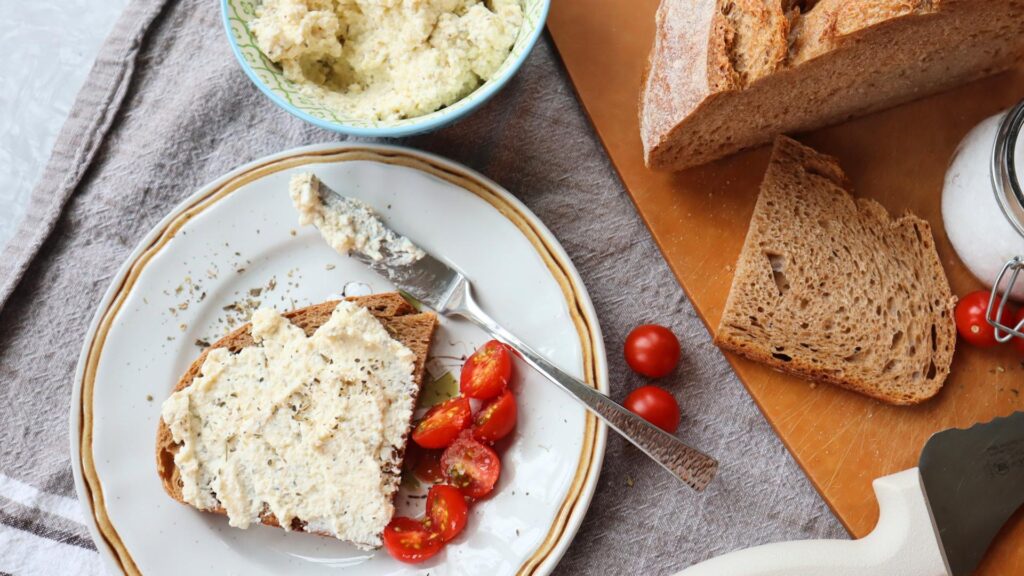 Table filled with herbed kefir cheese, cherry tomatoes and sourdough bread