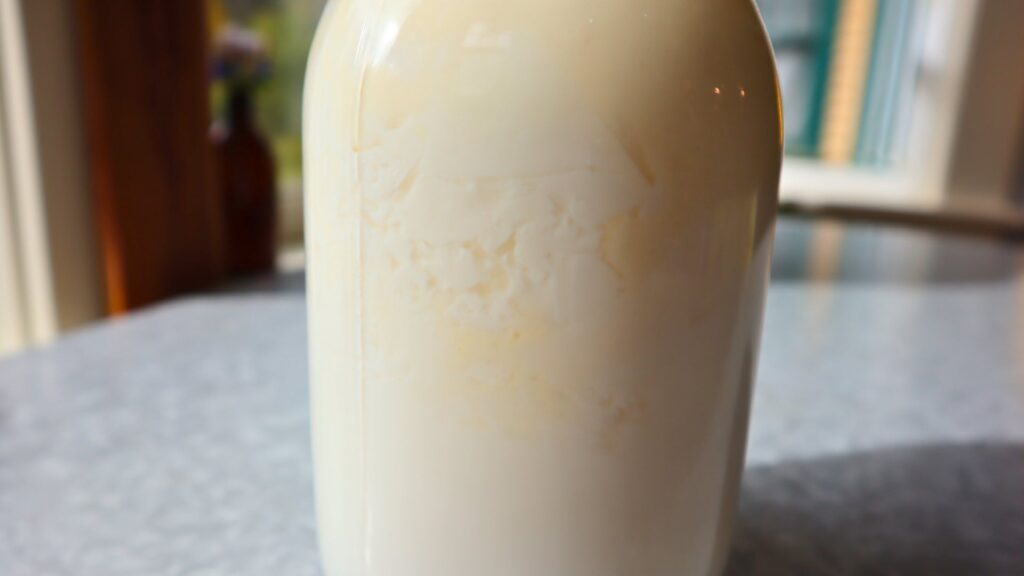Closeup of kefir in jar showing whey separating.