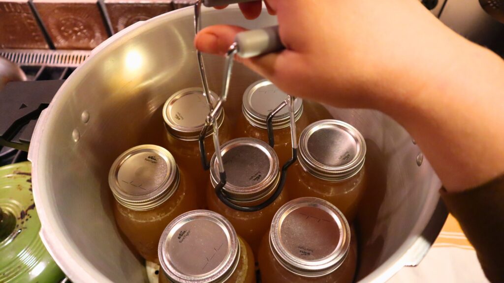 Using jar lifter to remove quarts of pressure canned bone broth.