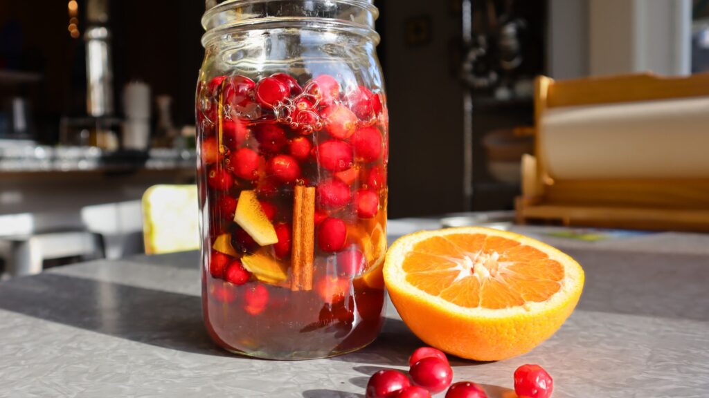 Cranberries, ginger, cinnamon and orange in a canning jar covered in honey to ferment.