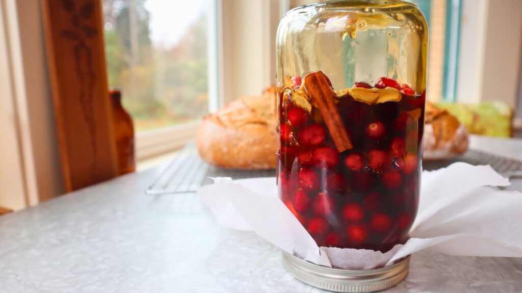 Upside down jar of fermenting honey cranberries with cinnamon.